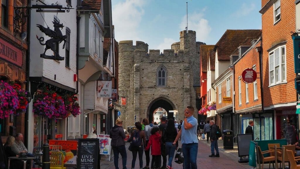 A street in Canterbury with people walking along and the medieval gates in the background