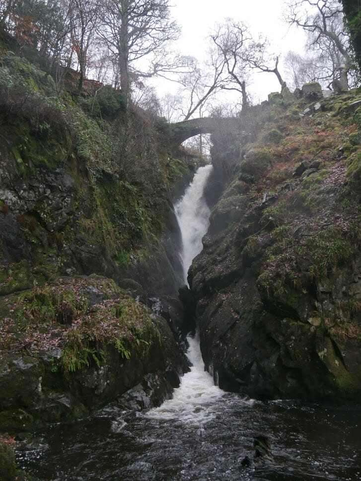 Aira Force waterfall in Ullswater running under an old stone bridge