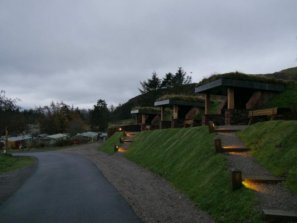 A line of hobbit holes on a grass ridge at The Quiet Site