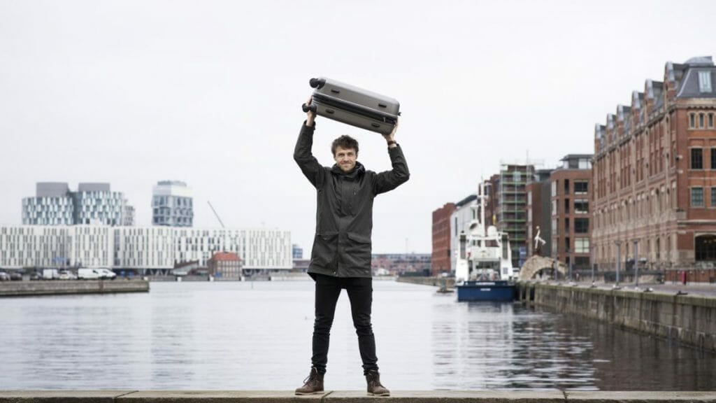 A man holding a suitcase above his head