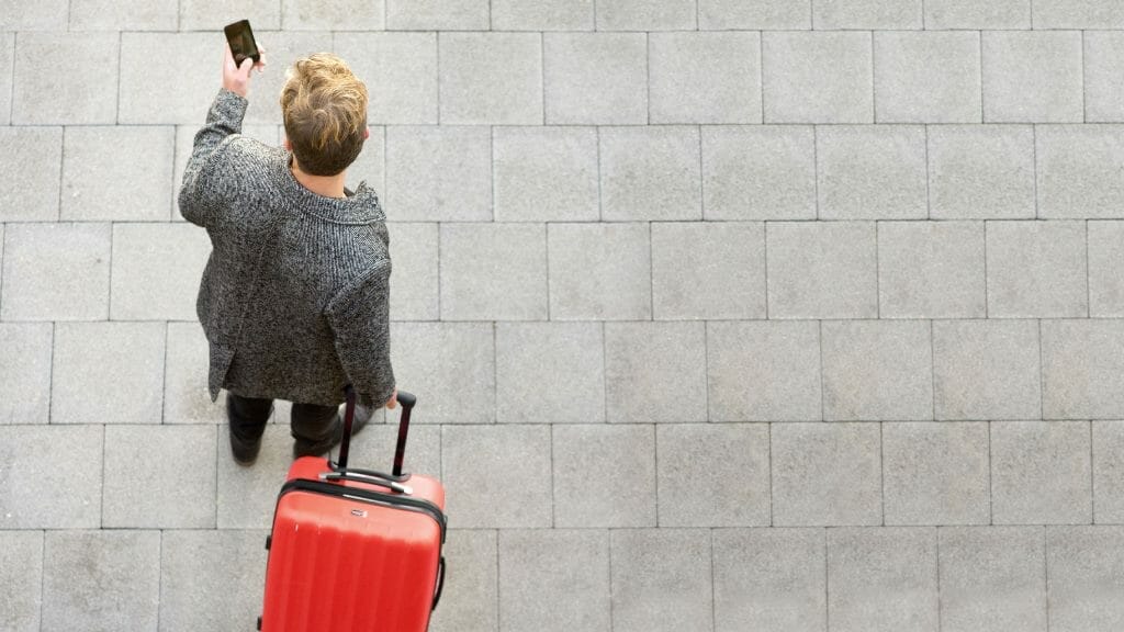 Someone looking at their phone while walking with luggage