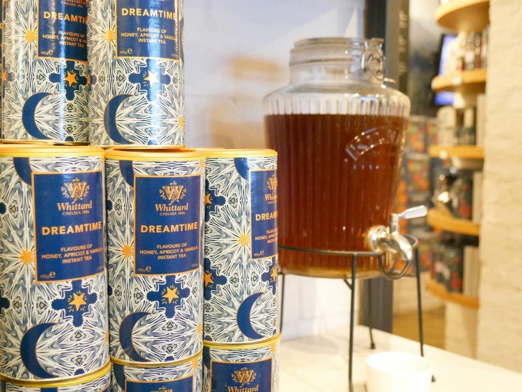 Tubs of loose leaf tea with a glass container of tea behind