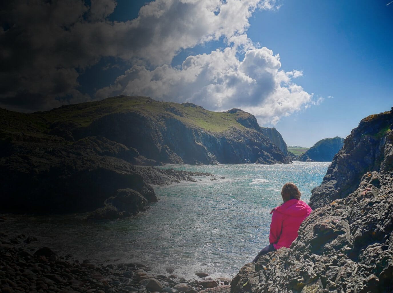 Kalyn on rocks looking out to sea in Cornwall with gradient overlay