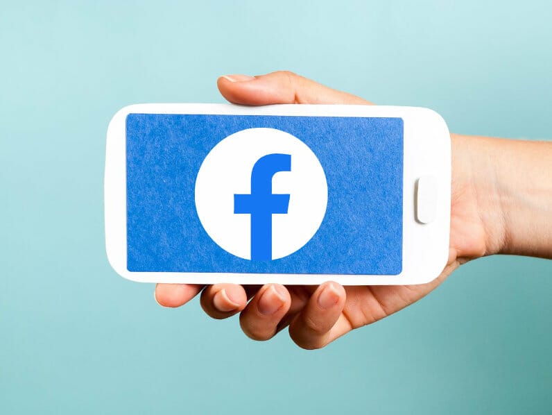 Hand holding phone with Facebook logo