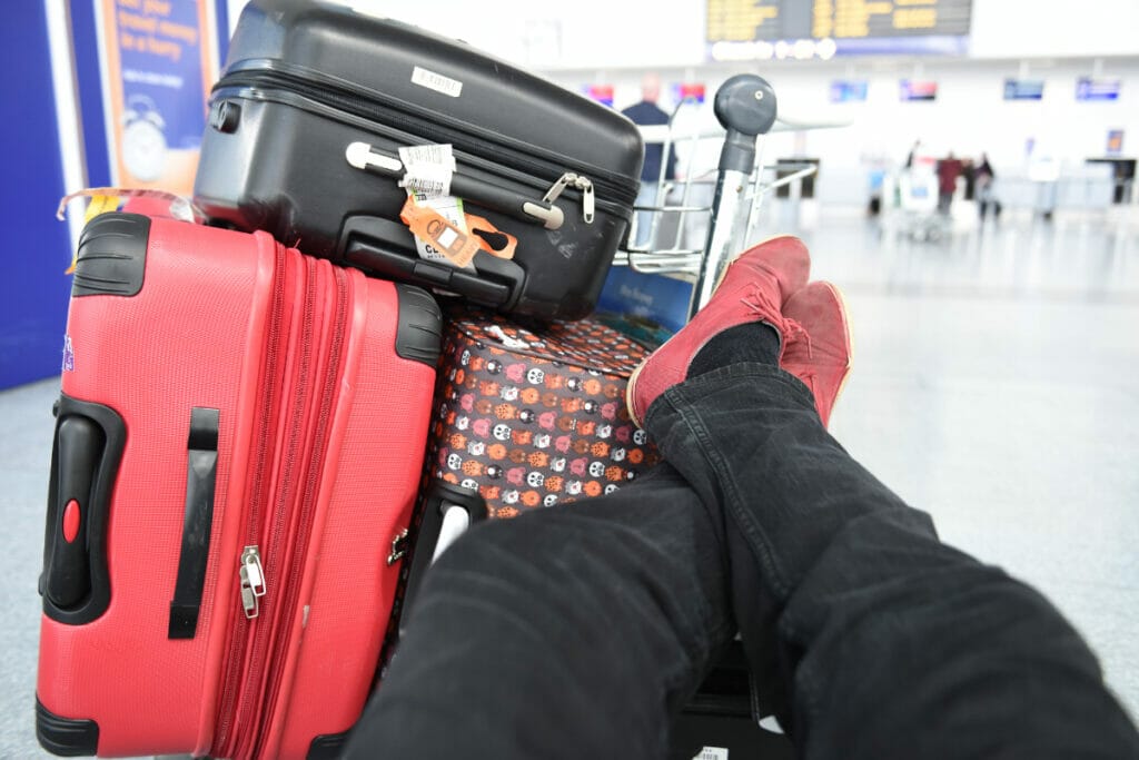 man's feet next to his suitcases