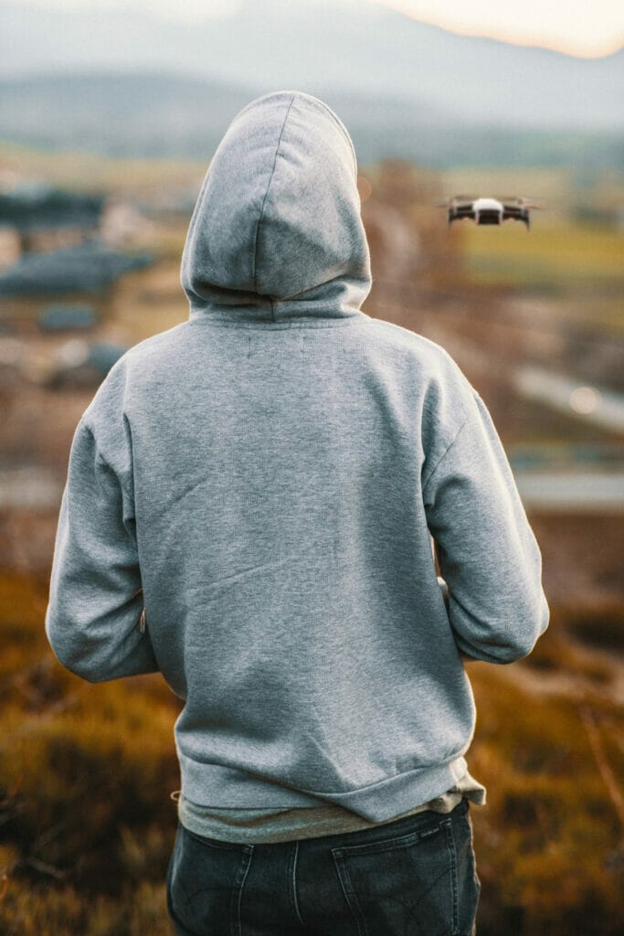 man in hoodie looking at drone