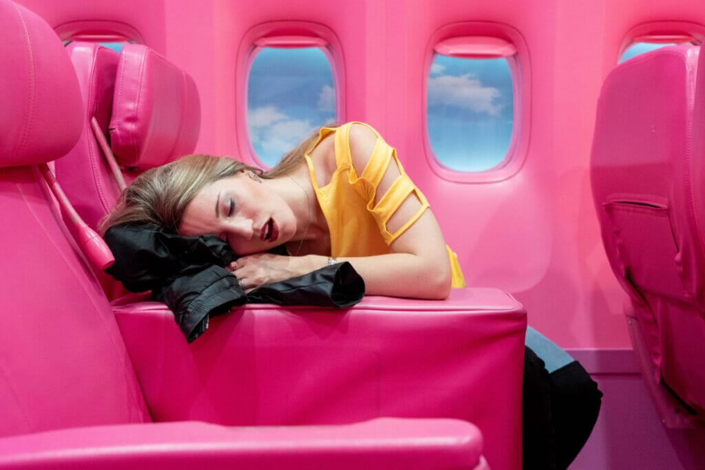 woman sleeping on plane with pink interior