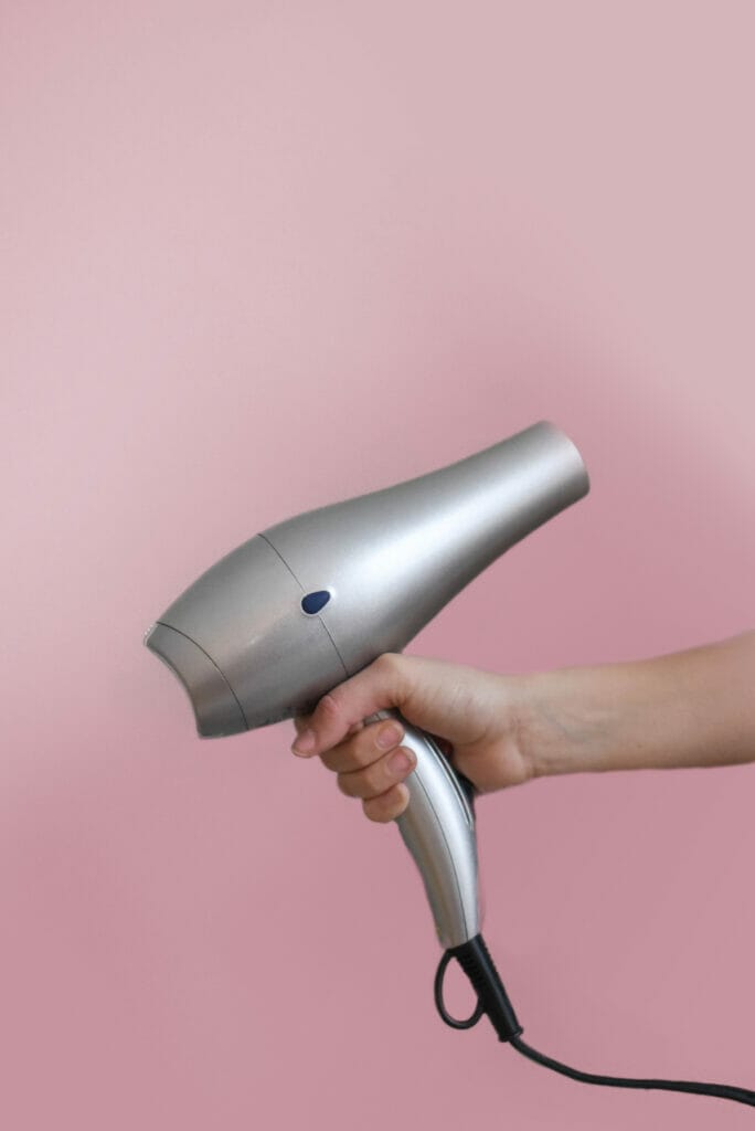 hand holding hair dryer with pink background